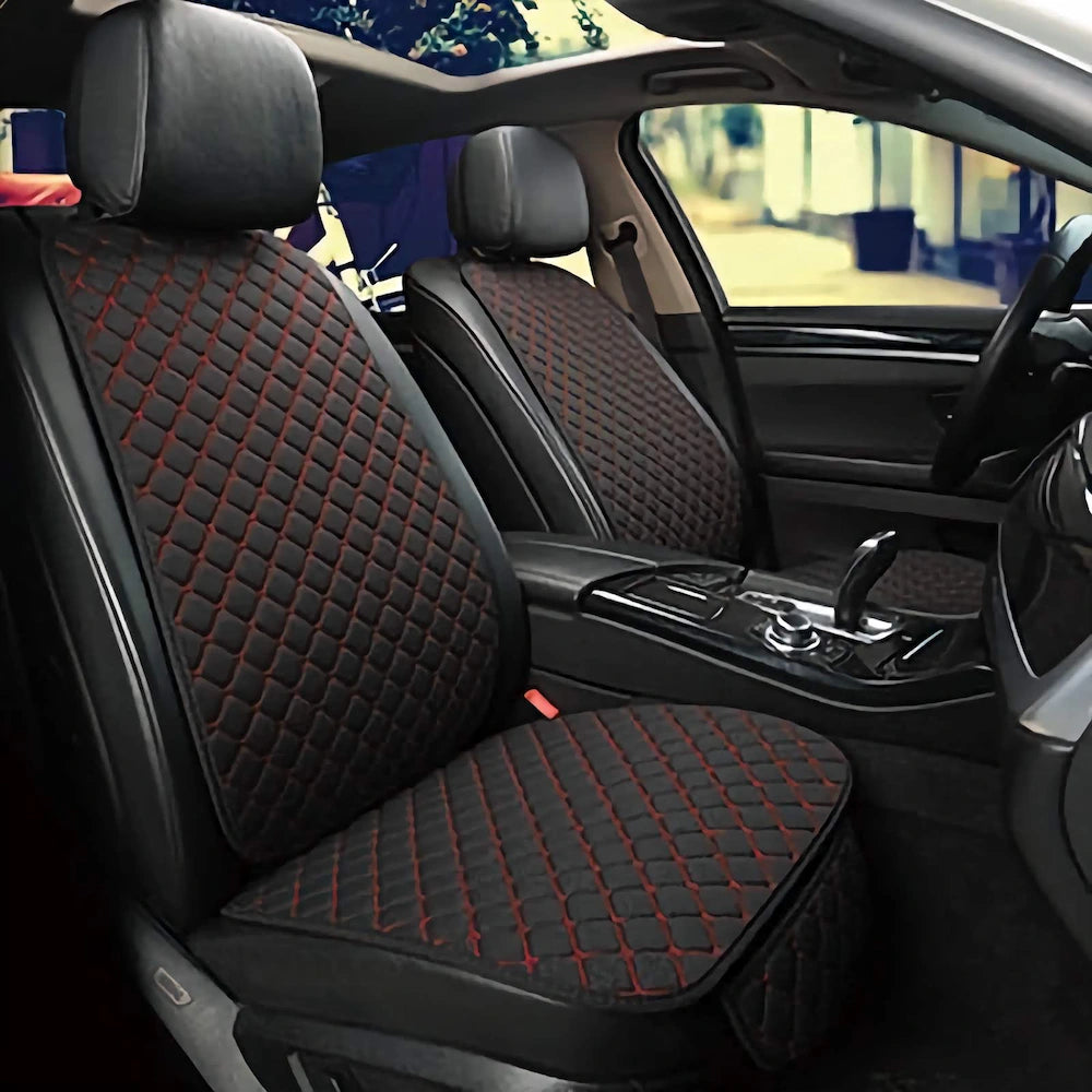 Car interior with black quilted seat covers featuring red stitching.